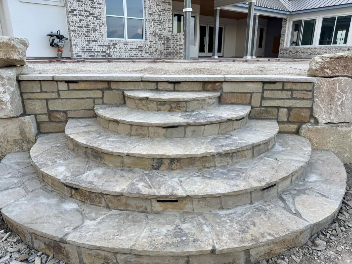 Rounded limestone steps fanning out from a stone seat wall at a new build